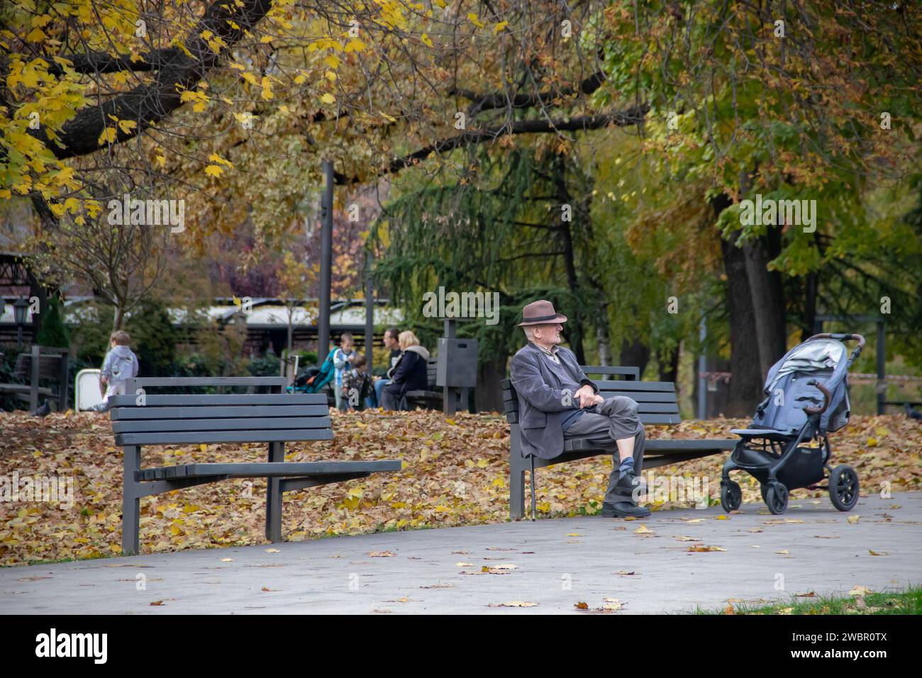 Nonno che porta il nipote per una passeggiata riposando alla panchina nel parco pubblico della città Foto Stock