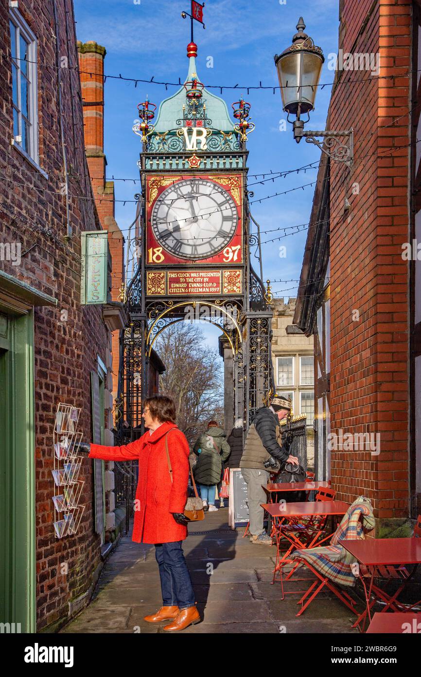 Donna che sceglie una cartolina da una selezione sulla parete di un negozio sulle mura romane vicino all'orologio Eastgate nella città del Cheshire di Chester, Inghilterra, Regno Unito Foto Stock