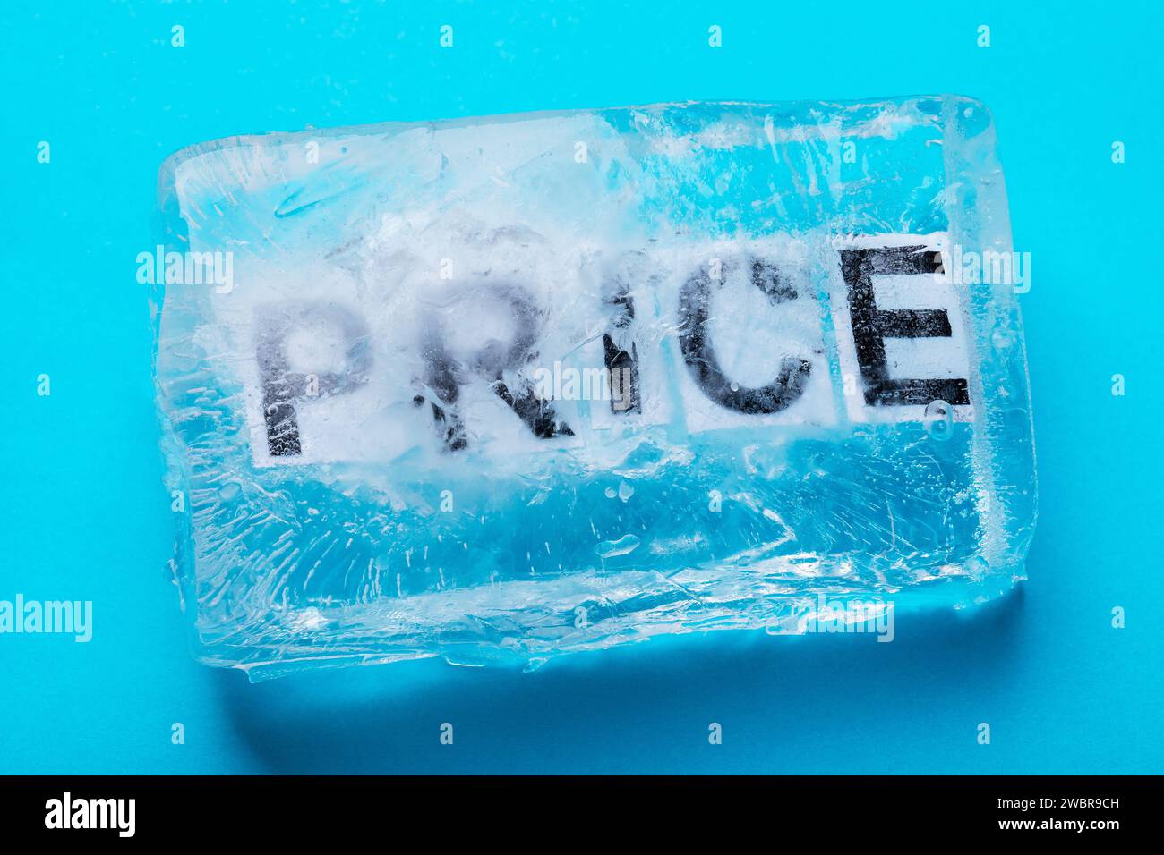 Testo congelato in un pezzo di ghiaccio su sfondo blu, concetto sul tema del congelamento dei prezzi Foto Stock