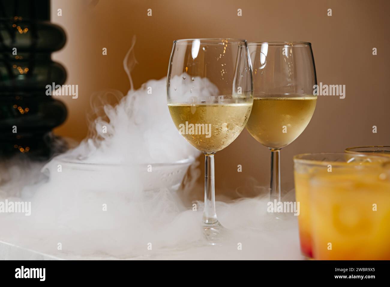 Eleganti bicchieri di vino bianco raffreddati con azoto liquido, creando un'atmosfera misteriosa e invitante. Foto Stock