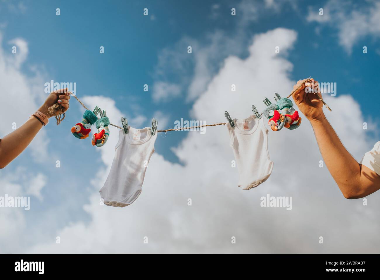 Due persone sono viste tenere una linea di lavanderia con indumenti per bambini Foto Stock