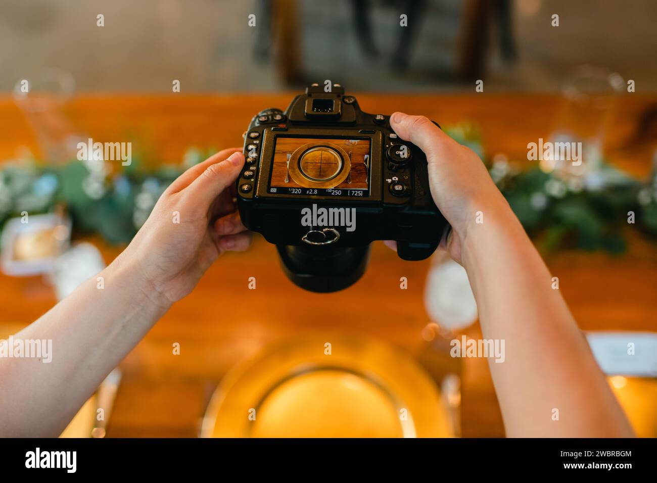 Primo piano delle mani del fotografo tenendo la fotocamera per scattare foto al tavolo Foto Stock