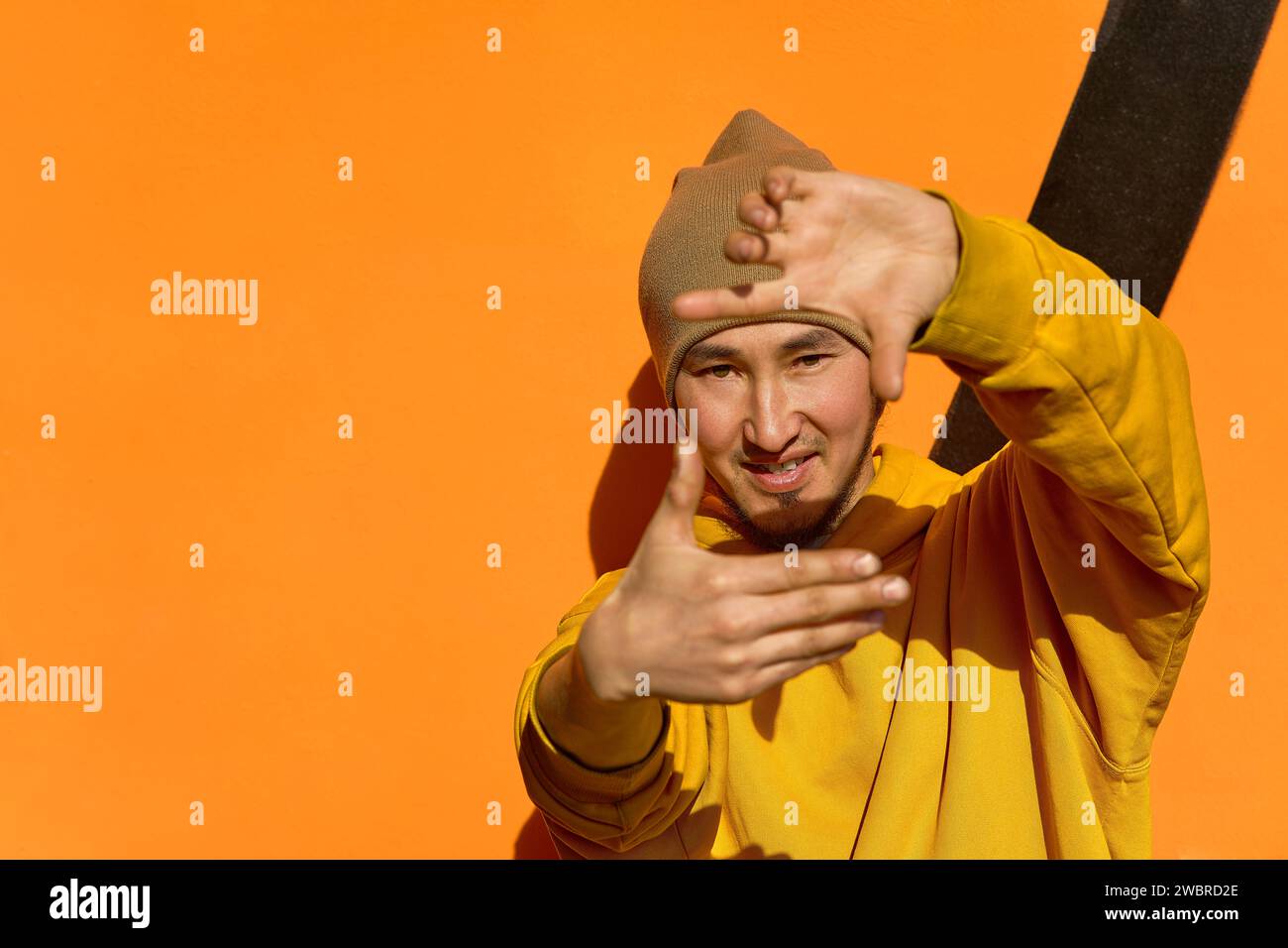 Un elegante ragazzo con una felpa gialla con cappuccio fa un gesto con le mani Foto Stock