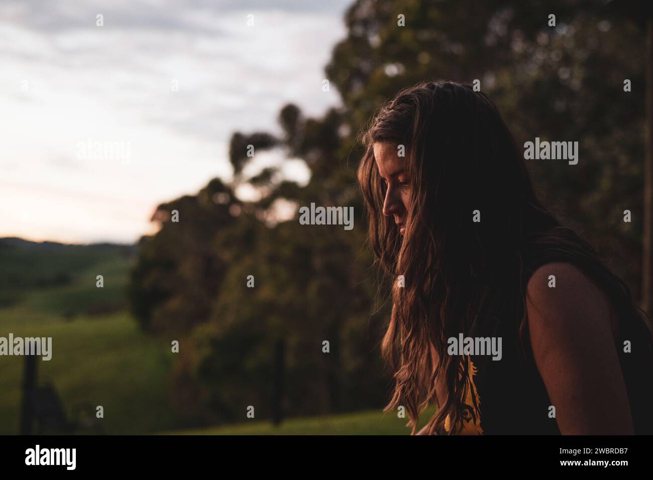 donna naturale in un'ora d'oro con alberi e colline ondulate Foto Stock