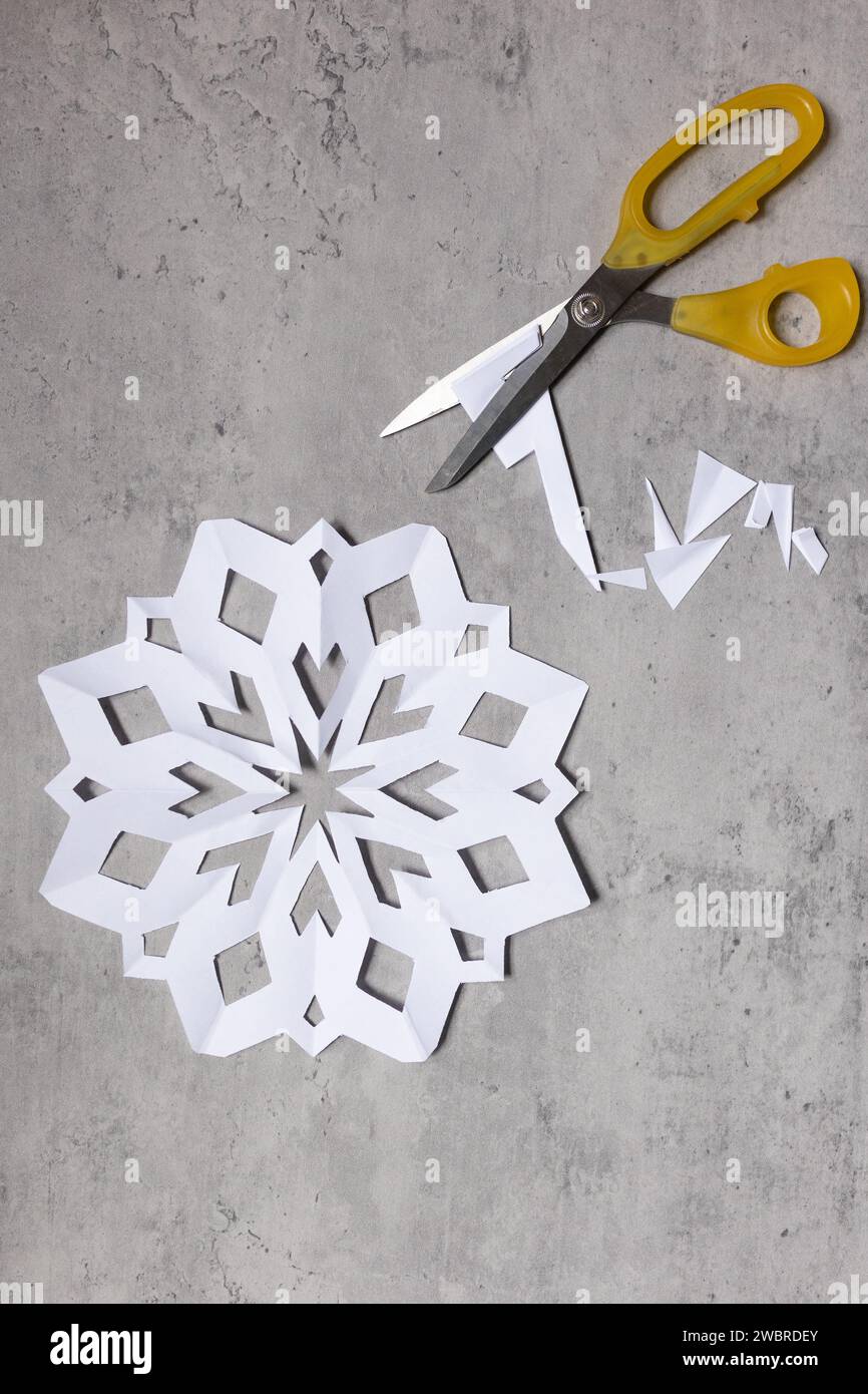 fiocco di neve di carta bianca con forbici Foto Stock