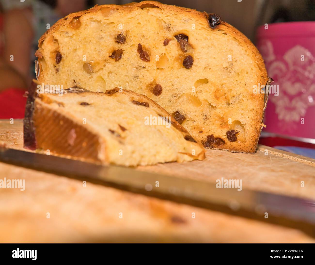 Panettone su tagliere, una fetta e un coltello per torte durante le feste Foto Stock