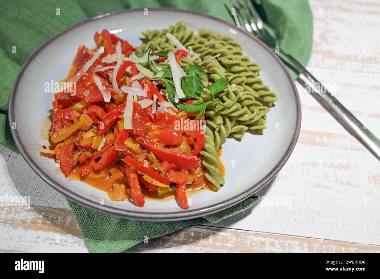 Pasto vegano sano da tagliatelle verdi a base di legumi con ragù vegetale rosso da peperone e pomodoro, alto in proteine, vitamine, fibre alimentari un Foto Stock