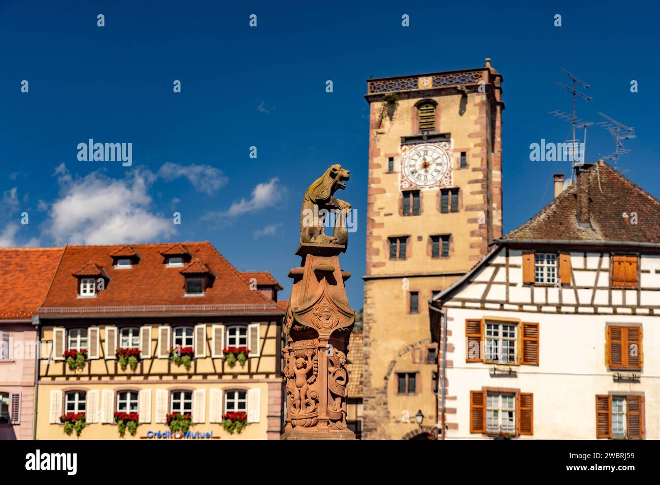 Löwe mit Stadtwappen am Marktbrunnen vor dem Rathaus und der Metzgerturm a Ribeauville, Elsass, Frankreich | scultura del leone della founta del Municipio Foto Stock