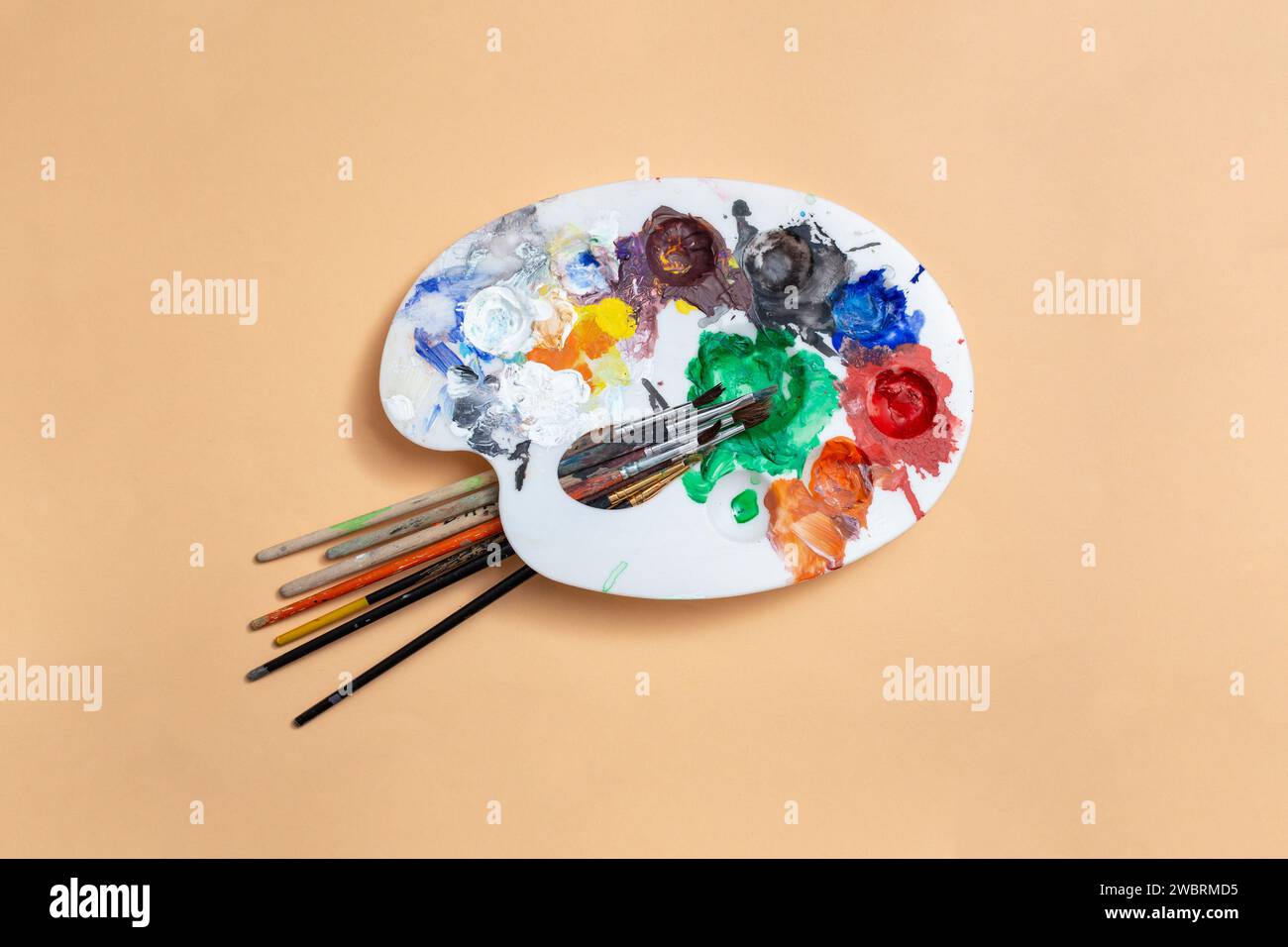 Tavolozza di colori con più sfumature e pennelli su sfondo beige, astratto Foto Stock