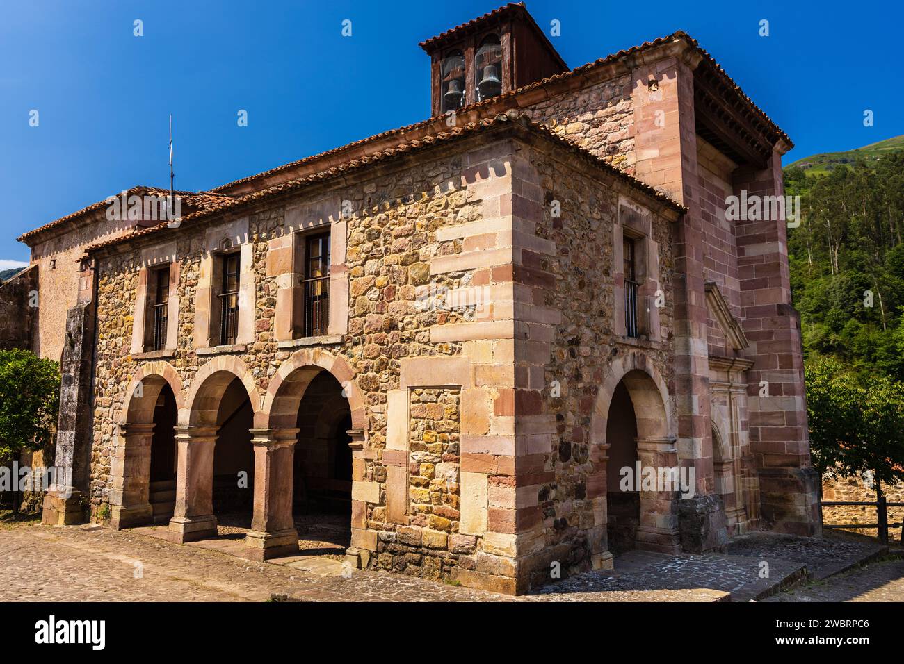 Facciata della vecchia chiesa in pietra di San Roque, un tempio a pianta a croce latina, tetti a coste e un portico a tre archi. Carmona, Cantabria, Spagna. Foto Stock Facciata della vecchia chiesa in pietra di San Roque, un tempio a pianta a croce latina, tetti a coste e un portico a tre archi. Carmona, Cantabria, Spagna. Foto Stock