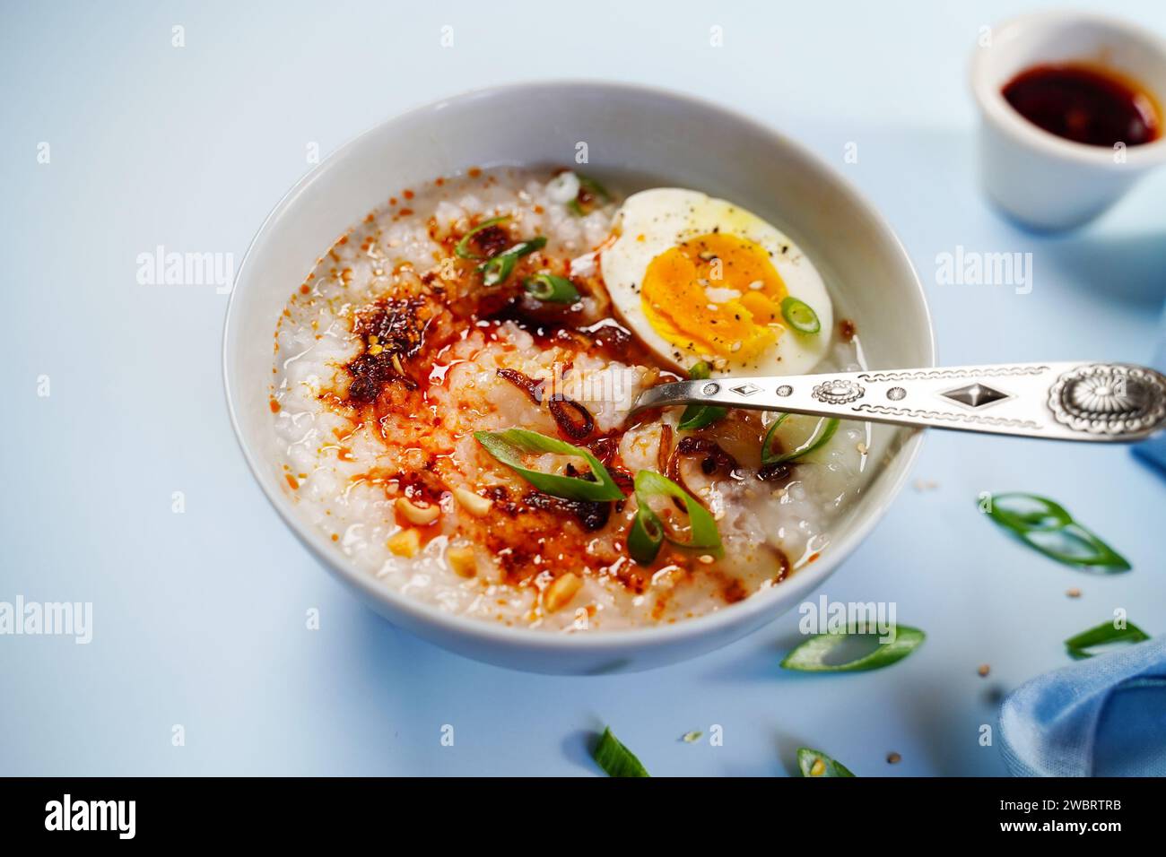Congee in stile cinese asiatico fatto in casa con scalogni fritti con uova sode e cipolle primaverili Foto Stock