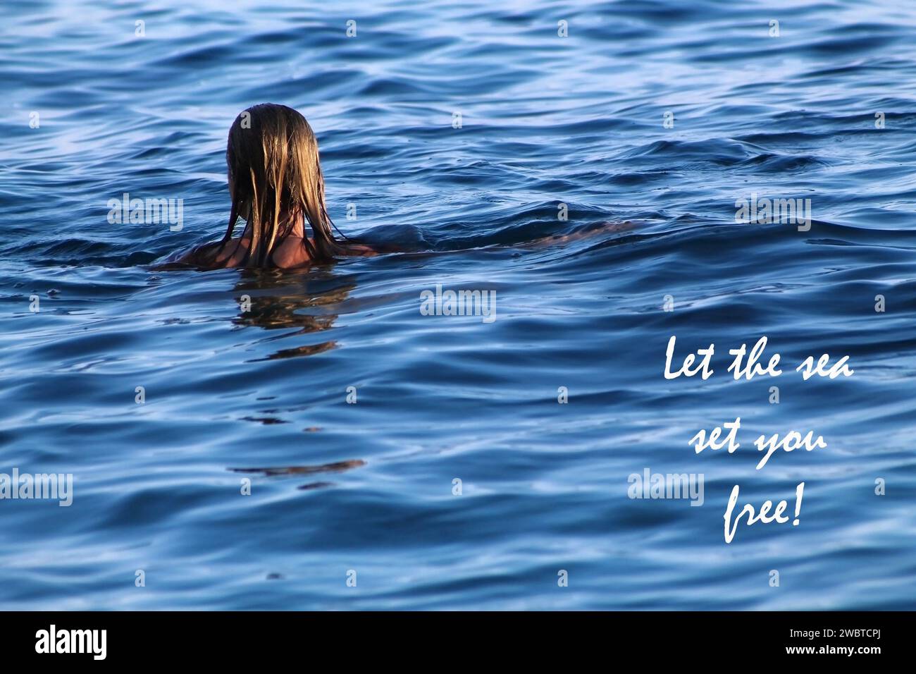 Una donna bionda che nuota nel mare con una citazione ispiratrice, lascia che il mare ti liberi. Foto Stock