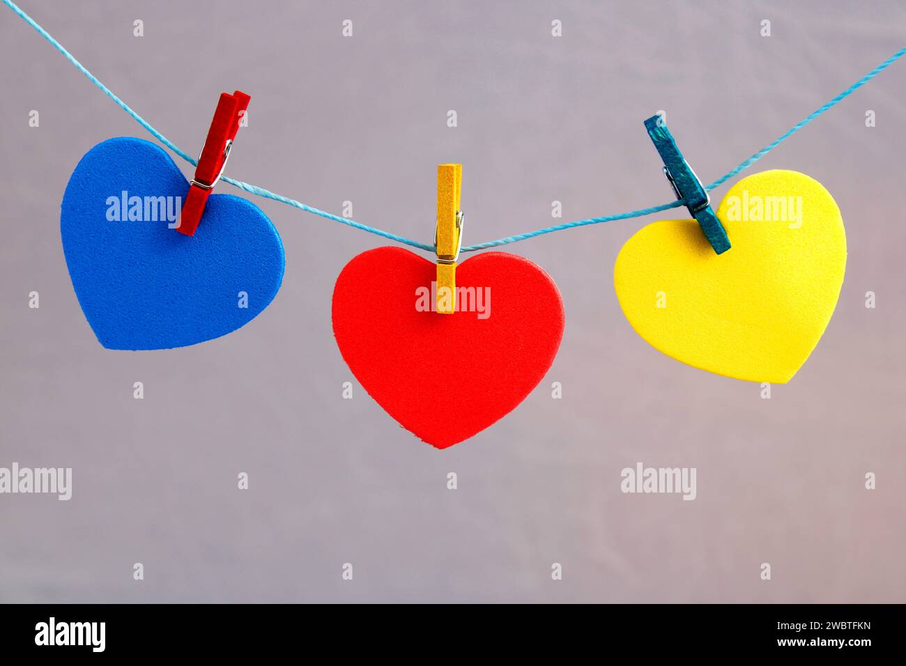 Cuori colorati attaccati alla corda con clothespins Foto Stock