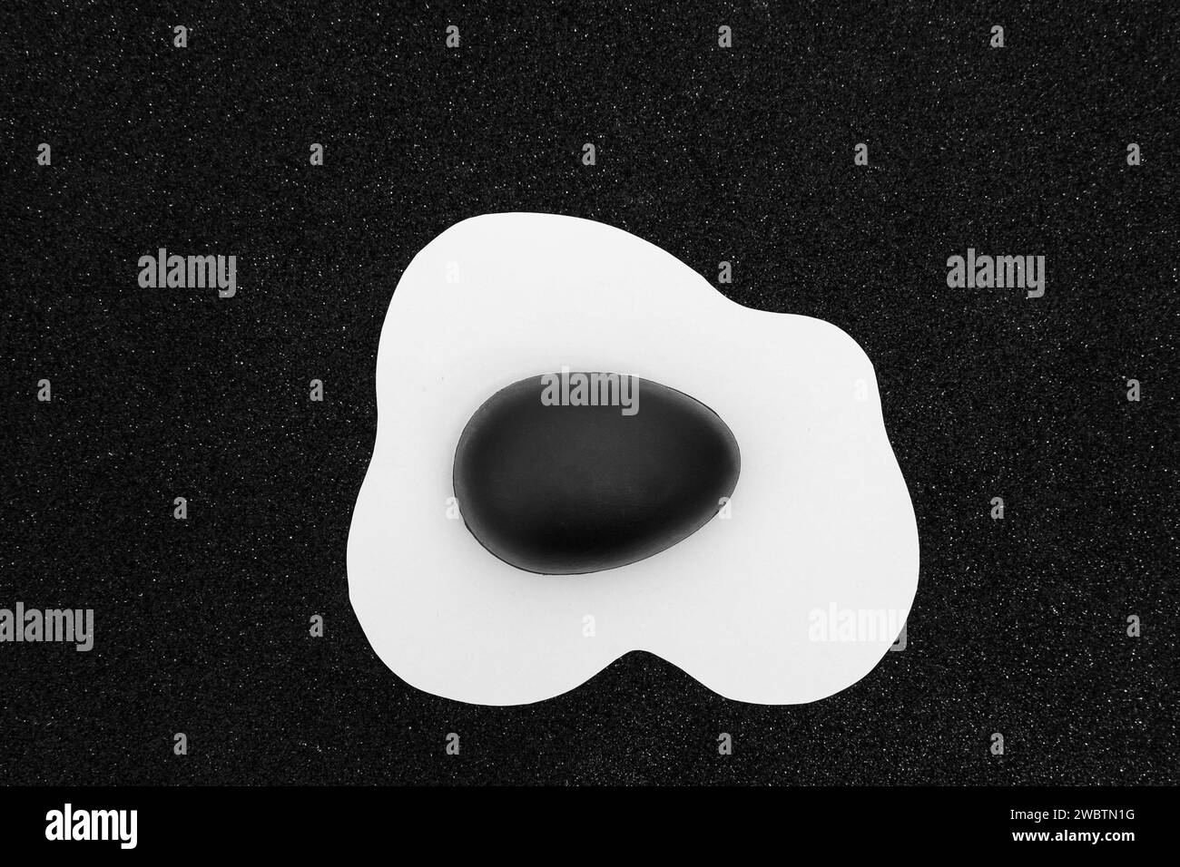Layout creativo composto da uovo strapazzato con uovo di Pasqua nero dipinto su sfondo nero. Sfondo minimale in bianco e nero. Vacanze primaverili Foto Stock
