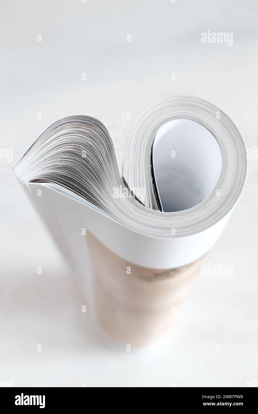 Rivista arrotolata, giornale, messa a fuoco selettiva e poco profonda, sfondo bianco, spazio di copia Foto Stock