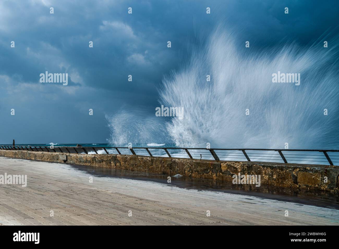 Onde oceaniche potenti che si infrangono sul bordo di un robusto molo, creando una magnifica mostra di forza naturale e bellezza Foto Stock