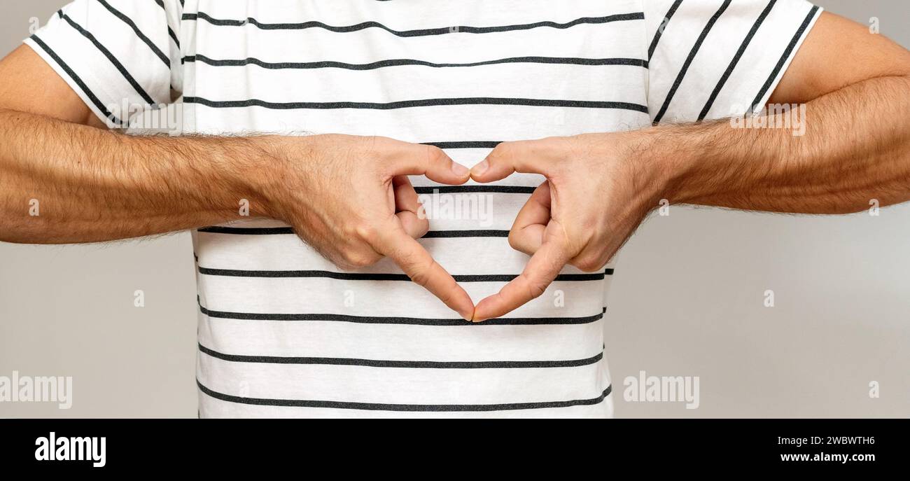 Persona maschile irriconoscibile gestisce la mano il cuore davanti al petto. Foto Stock
