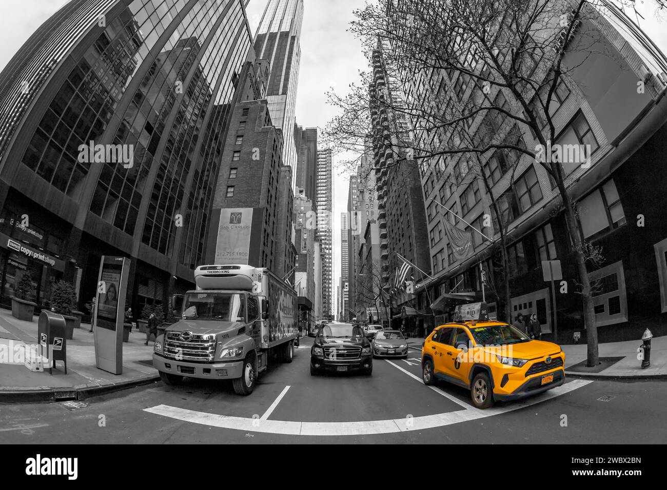 NEW YORK, MANHATTAN - 6 MARZO 2020: Edifici e traffico a Manhattan con tipico taxi giallo visto dal livello della strada. Processina in bianco e nero. Foto Stock