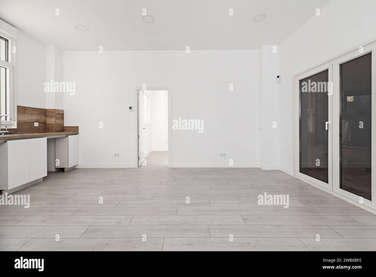 Cucina a vista rinnovata di recente con mobili in legno bianco, ripiano in legno con splash back in una casa al piano terra Foto Stock
