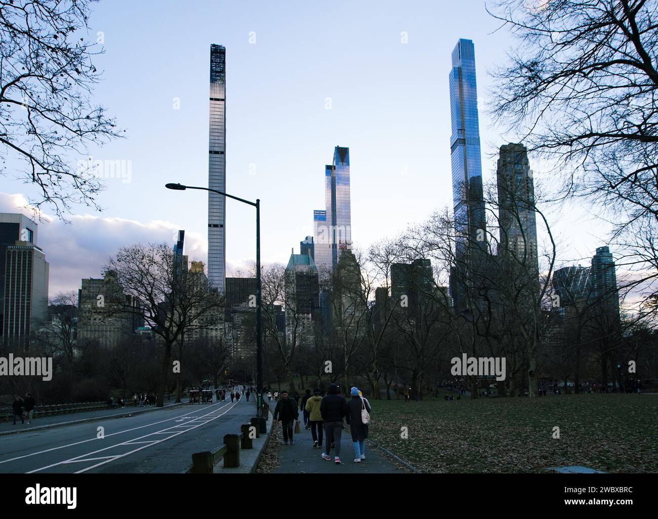 Un gruppo di persone che passeggiano lungo un sentiero pavimentato fiancheggiato da vegetazione lussureggiante su entrambi i lati in un ambiente urbano Foto Stock