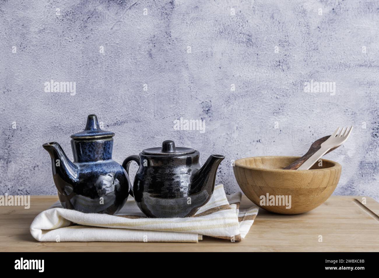 Una natura morta con utensili da cucina in legno e brocche in porcellana blu e nera su un asciugamano da cucina Foto Stock