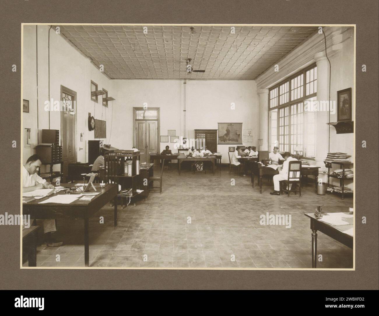 Interni di uffici con impiegati e mobili della fabbrica di zucchero Meritjan a Kediri su Java, c. 1925 - c. 1930 Fotografia parte dell'album fotografico con registrazioni di quattro fabbriche di zucchero su Java. Cartone Kediri. carta. supporto fotografico zucchero con stampa gelatina argento. piantagione. piante ed erbe: canna da zucchero. ufficio ( amministrazione). Interno  rappresentazione di un edificio Indie orientali olandesi, il. Kediri Foto Stock