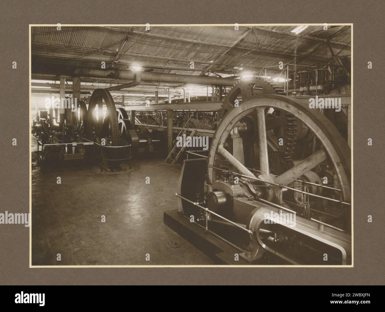 Macchine in una sala della fabbrica di zucchero Meritjan a Kediri su Java, c. 1925 - c. 1930 Fotografia parte di album fotografico con registrazioni di quattro fabbriche di zucchero su Java. Cartone Kediri. carta. supporto fotografico zucchero con stampa gelatina argento. piantagione. piante ed erbe: canna da zucchero. Interni di fabbrica, officina meccanica delle Indie Orientali olandesi, Kediri Foto Stock