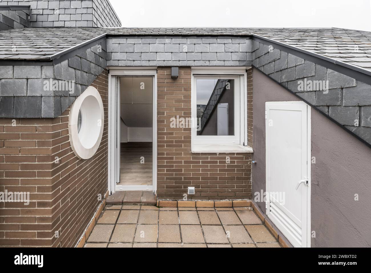 Piccola terrazza di una casa con un oblò, tetti con piastrelle di ardesia nera Foto Stock
