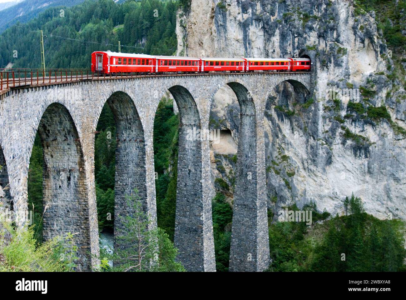 Treno rosso della Rhätische Bahn svizzera, compagnia ferroviaria Retica o Glacier Express sul viadotto Landwasserviadukt, vicino alla città di Filisur, Grigioni, Svizzerlan Foto Stock