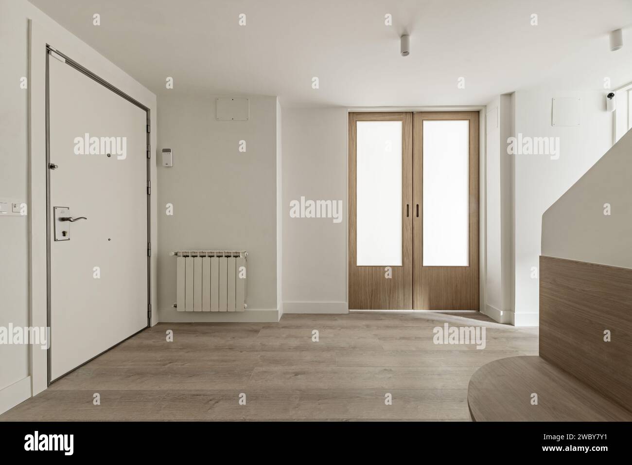 Sala di una casa con pareti lisce dipinte di bianco, porte scorrevoli in legno e vetro opaco e pavimenti in parquet di quercia Foto Stock