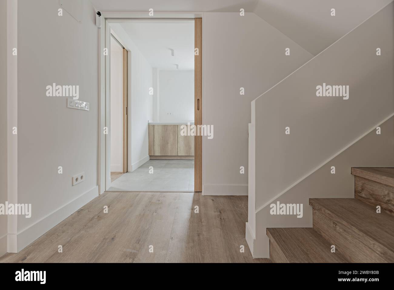 Lobby di una casa con pareti dipinte di bianco liscio, scalinate e pavimenti in legno coordinati. Foto Stock