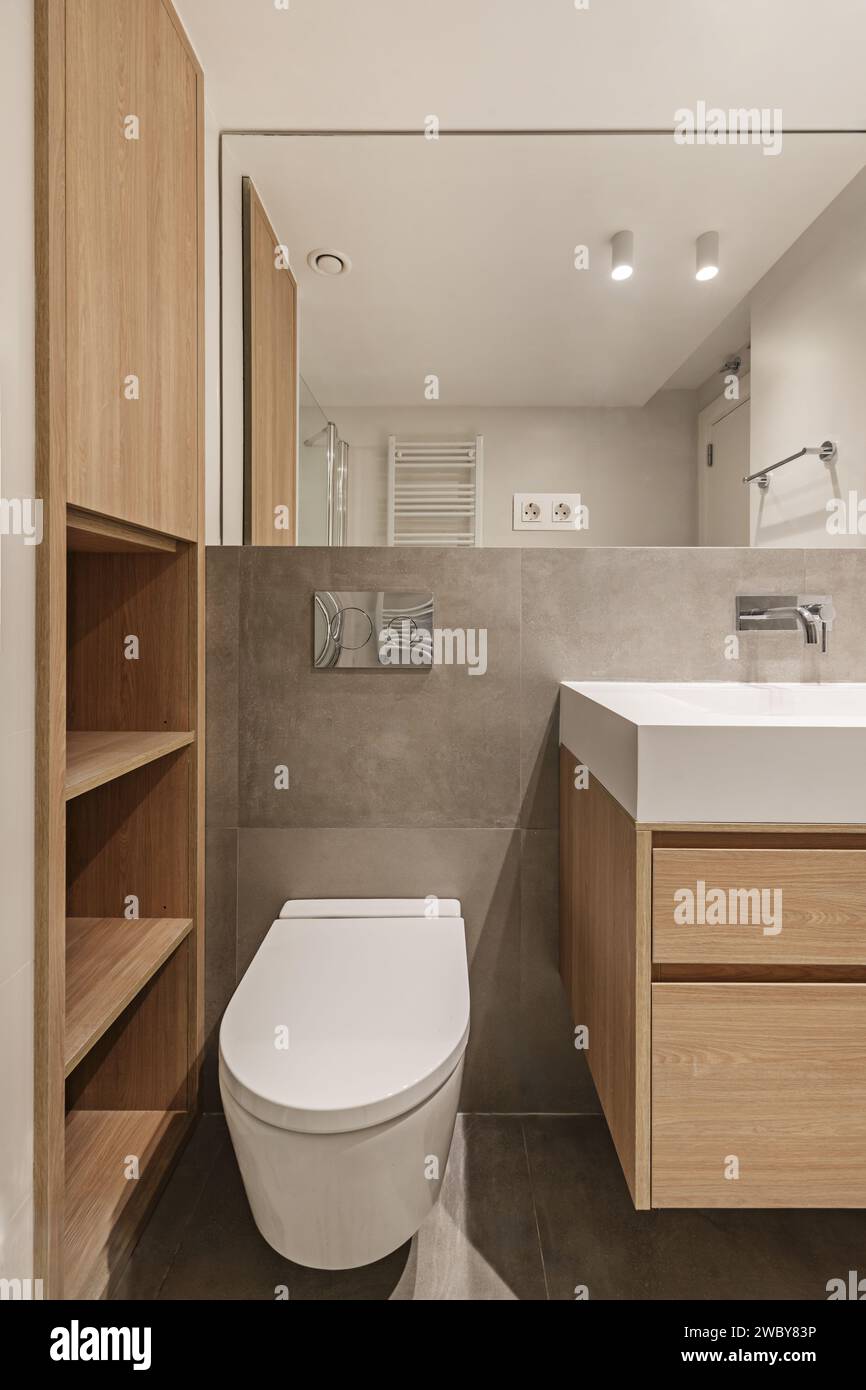 Gabinetto di un piccolo bagno con mobili in quercia e uno specchio senza cornice sulla parete Foto Stock