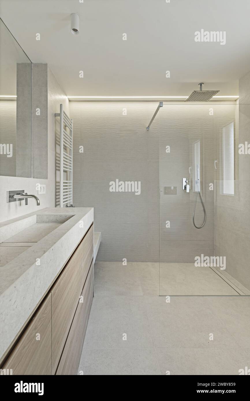 Un bagno spazioso dal design moderno con un lavandino in marmo color crema che si abbina ai pavimenti e alle pareti Foto Stock