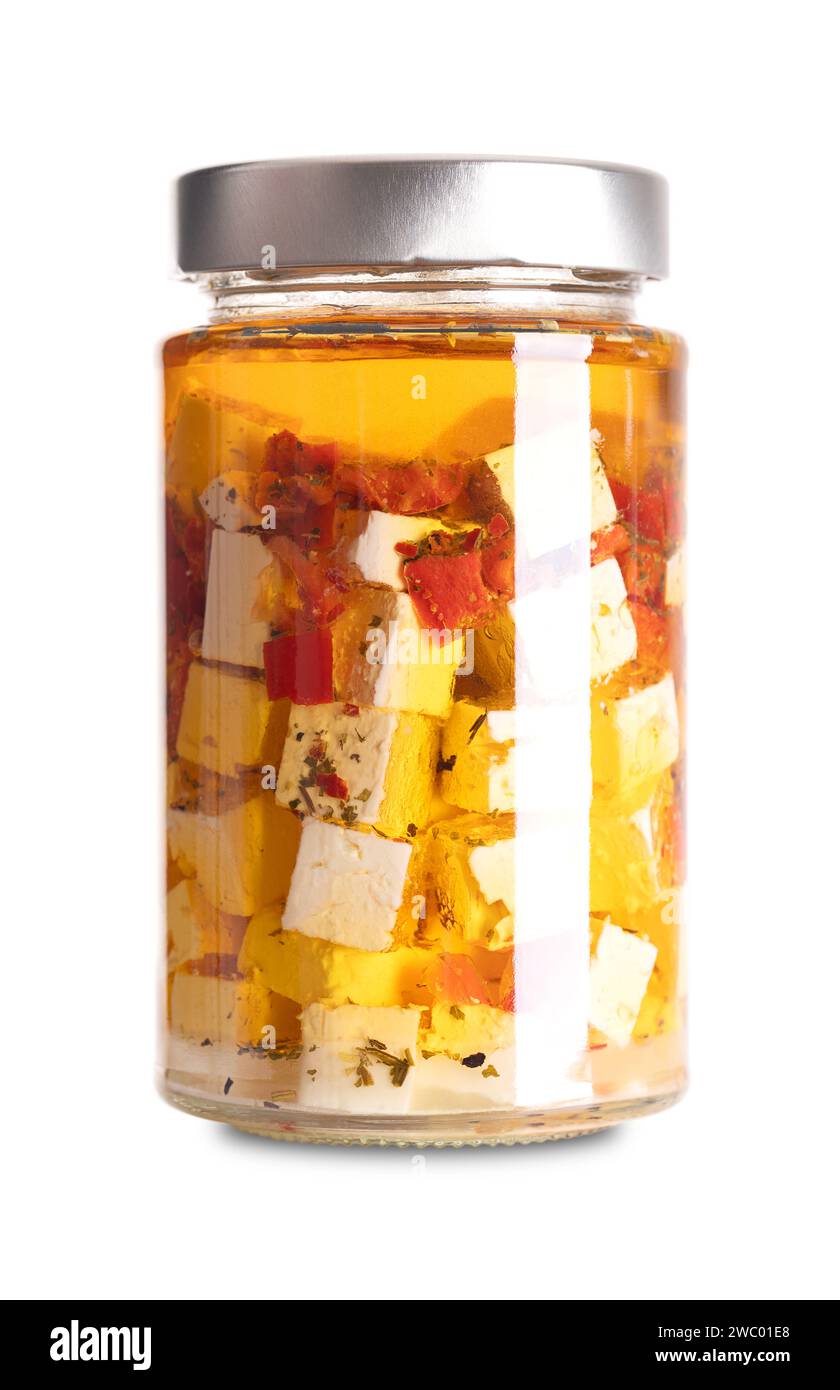 Feta a cubetti in olio, con peperoncino rosso e peperoncino, in vaso di vetro. Formaggio greco, stagionato in salamoia, tagliato a blocco, conservato in olio speziato. Foto Stock