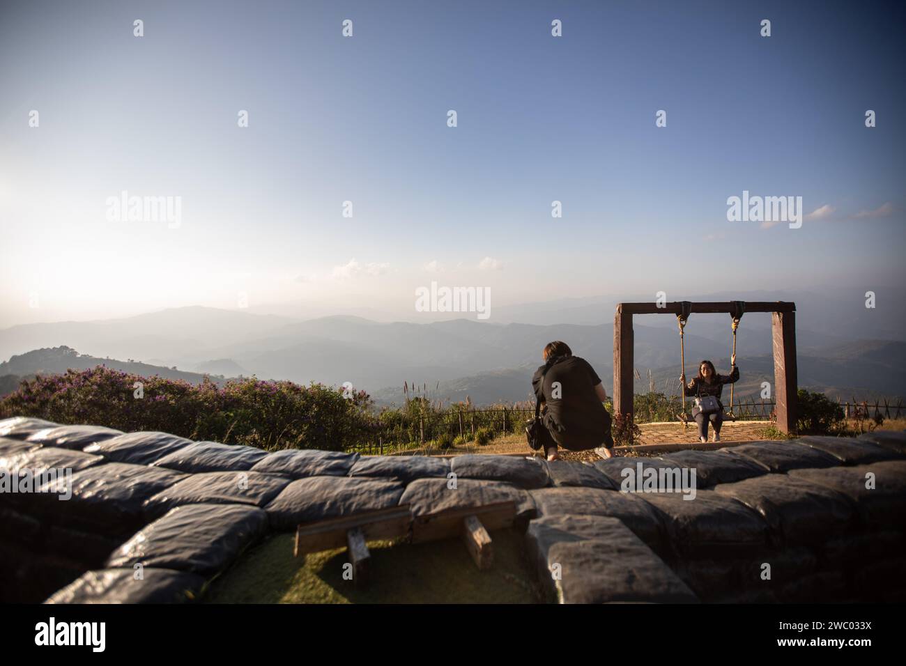 I turisti locali scattano foto su un'altalena con la montagna del Myanmar sullo sfondo. L'avamposto militare di Chang Moob ora trasformato in un luogo di attrazione turistica, era un luogo dell'esercito reale tailandese per prevenire il traffico di droga e tenere d'occhio altre attività sospette sul lato del Myanmar (soprattutto negli anni '1990). Chiamata anche "trincee di Doi Tung", inizia con uno stretto sentiero attraverso alte recinzioni di bambù prima di raggiungere il punto principale con profonde trincee lungo le sezioni più settentrionali del confine tra Thailandia e Myanmar, con una vista mozzafiato delle montagne del Myanmar. Foto Stock