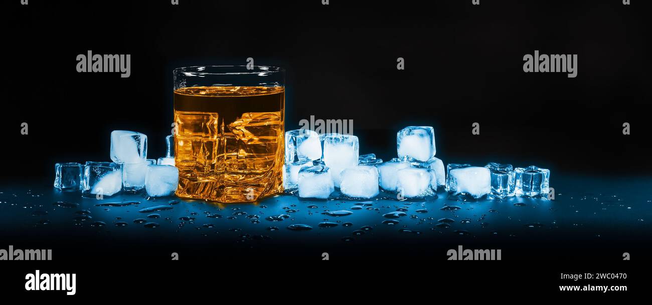 Bicchiere di whisky su uno sfondo scuro contro lo scioglimento dei cubetti di ghiaccio Foto Stock