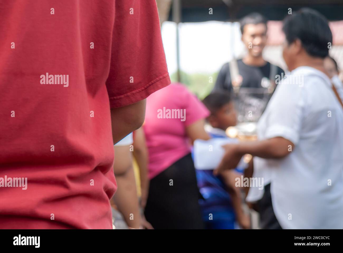 Persone in attesa di ricevere la distribuzione di cibo alle persone che vengono al festival di Kathin per fare il merito in Thailandia Foto Stock