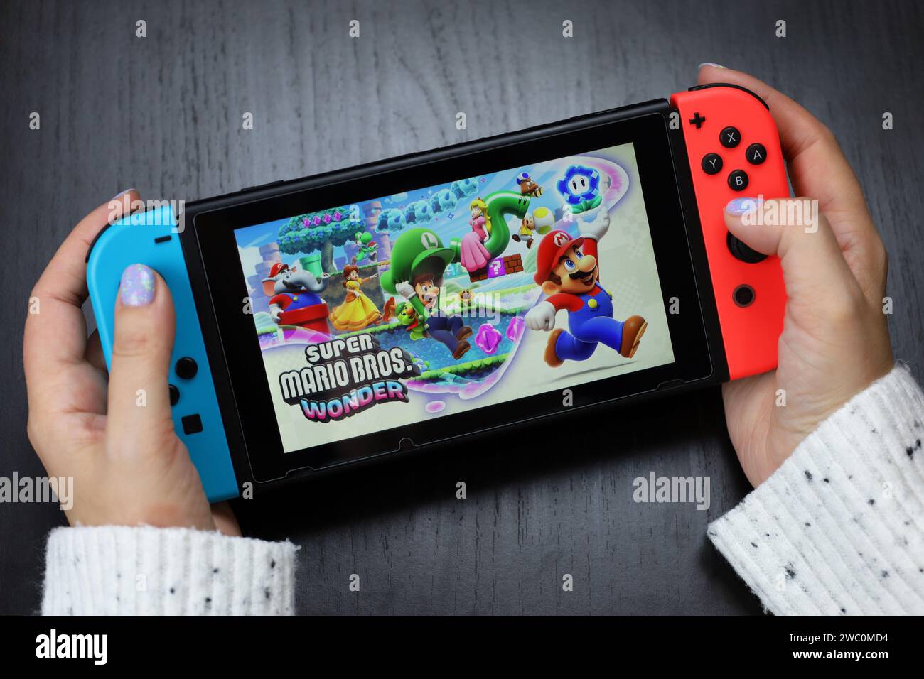 Ragazza che gioca a Super Mario Bros. Wonder game sulla console Nintendo Switch in modalità portatile Foto Stock