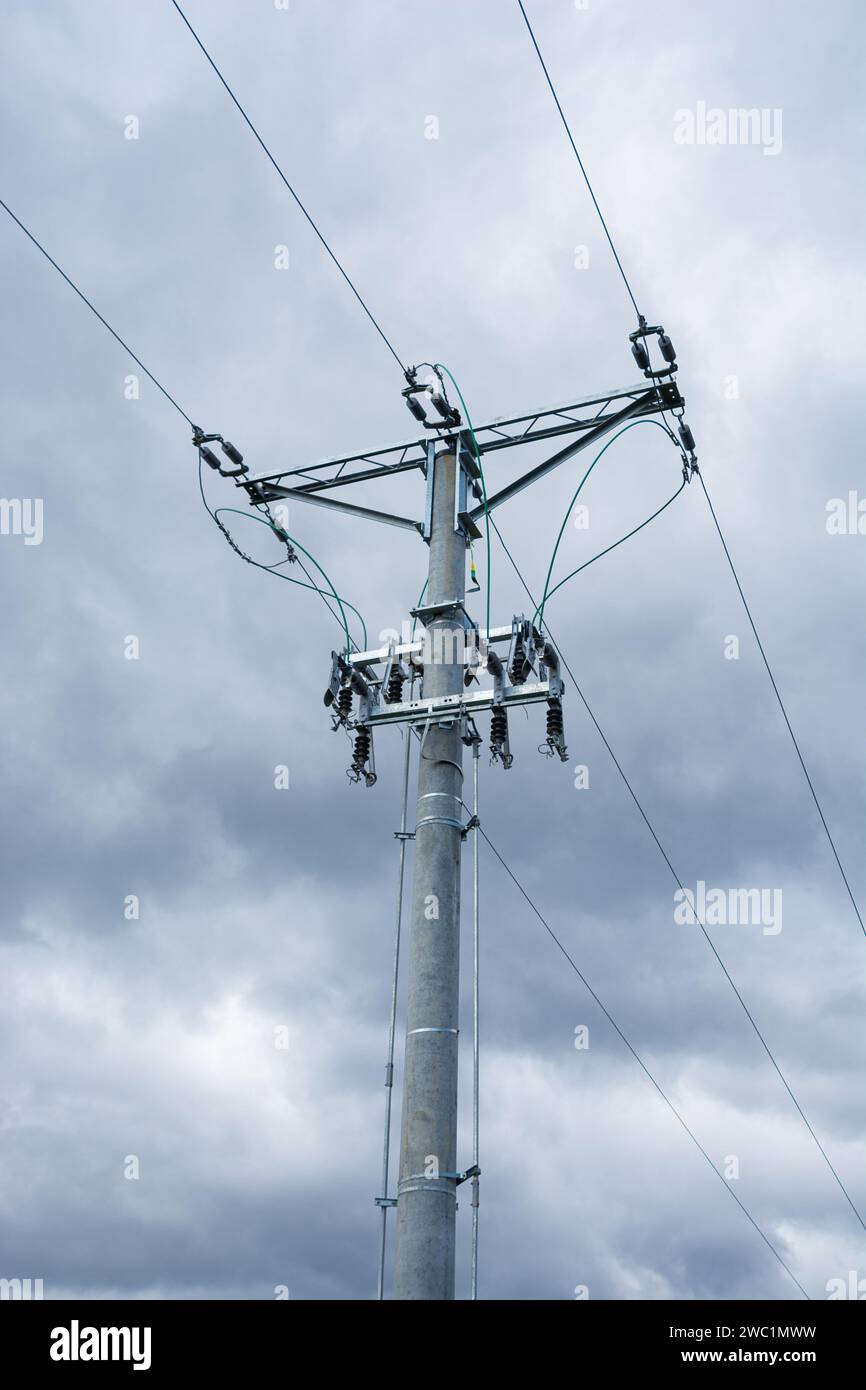 linea aerea a media tensione, asta con isolanti e sezionatori, nuvole scure sullo sfondo Foto Stock