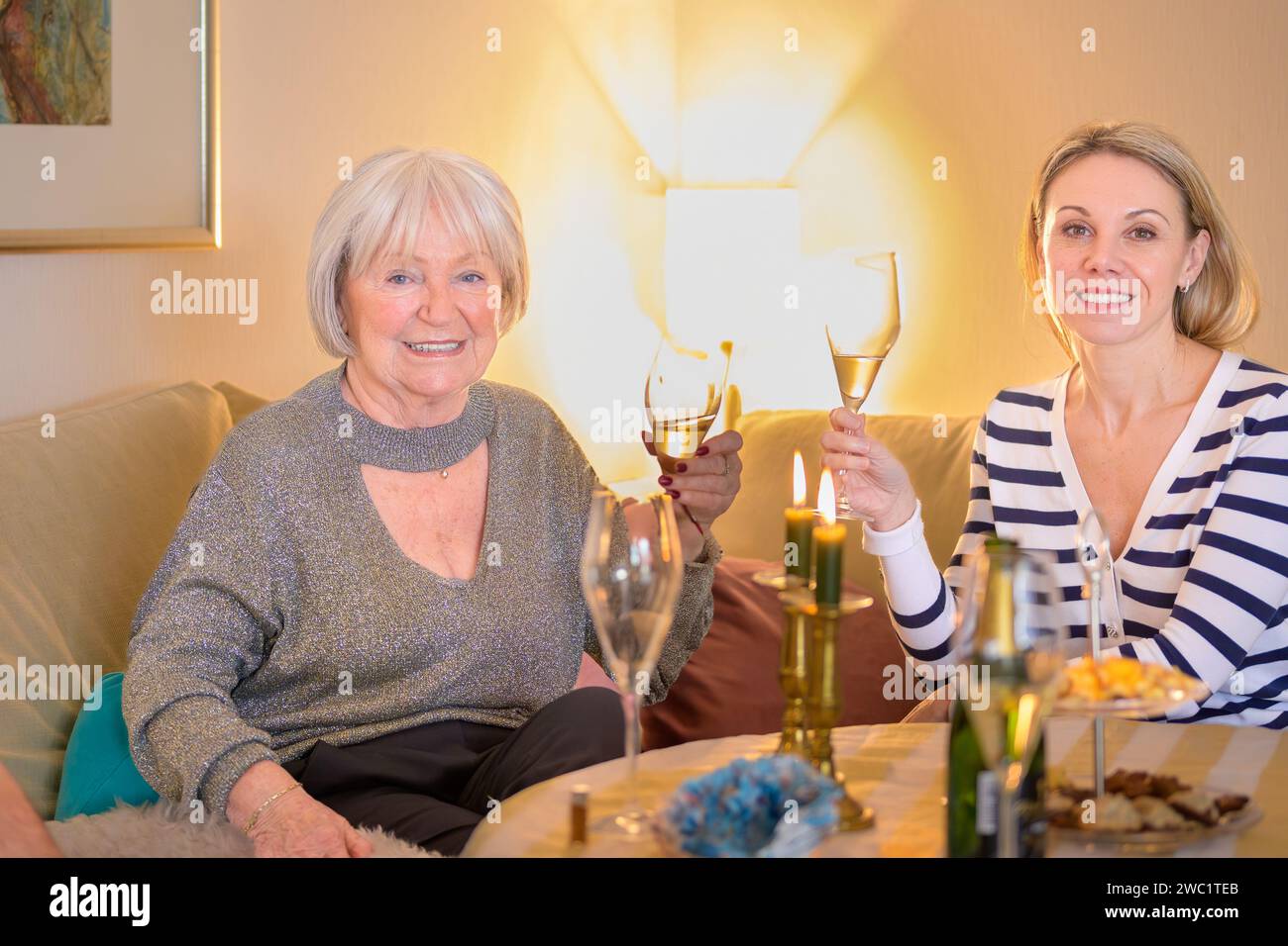Madre e figlia sono sedute insieme sul divano e brindano con champagne Foto Stock