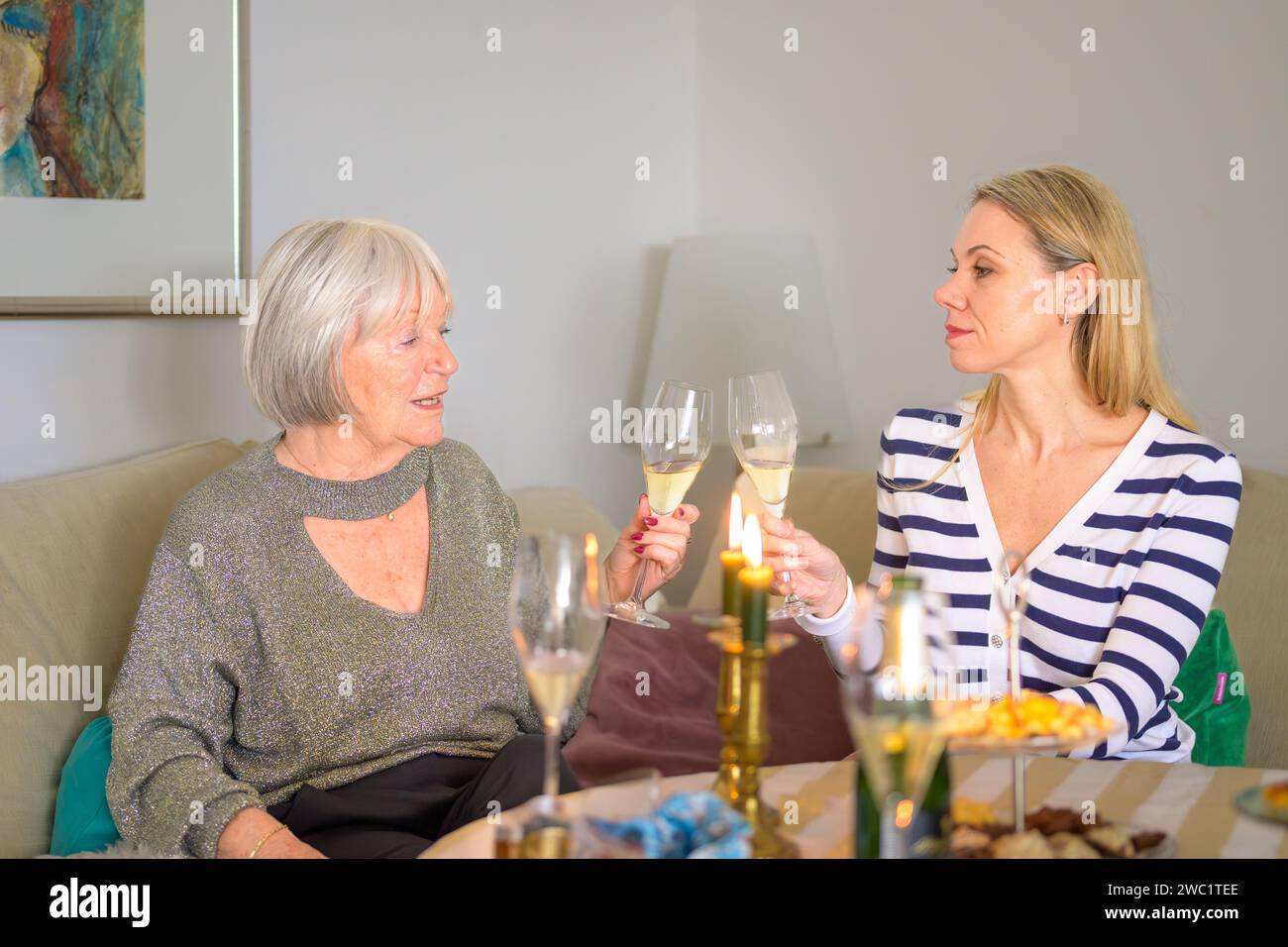 Madre e figlia sono sedute insieme sul divano e brindano con champagne Foto Stock