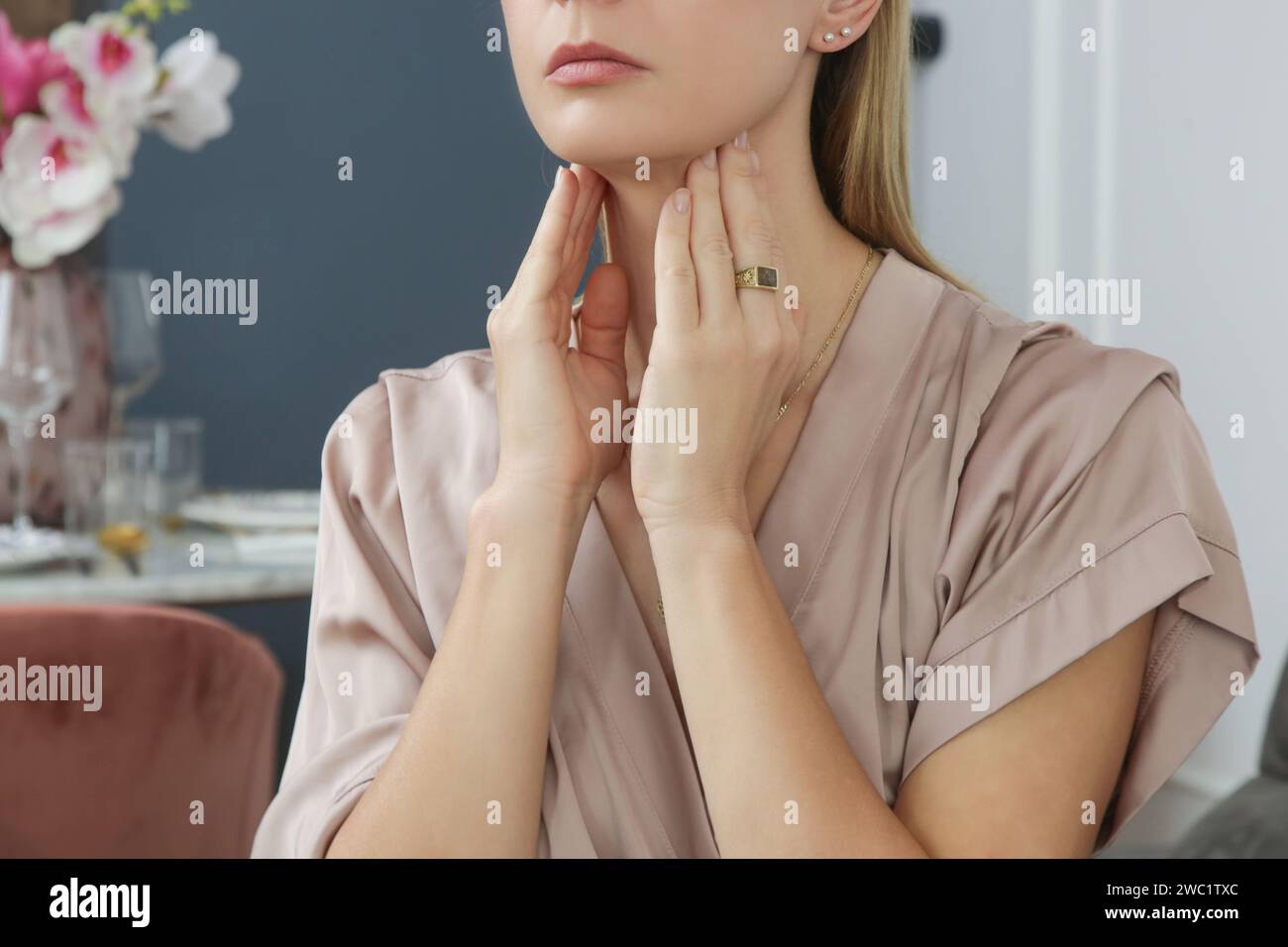 Donna caucasica che si tocca la gola. Mal di gola, raffreddore, influenza, tonsillite o problema della ghiandola tiroidea Foto Stock
