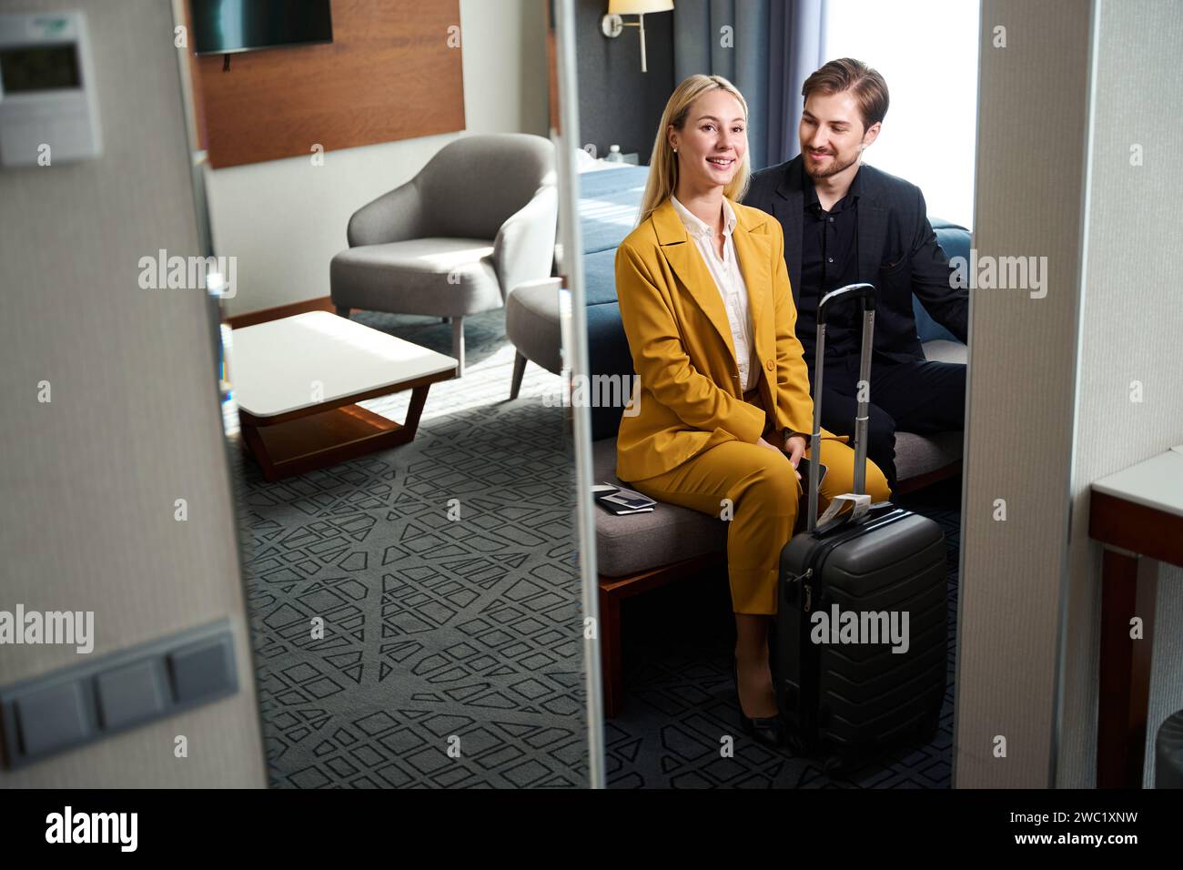 Una giovane coppia soddisfatta seduto sulla panchina nella camera d'albergo Foto Stock