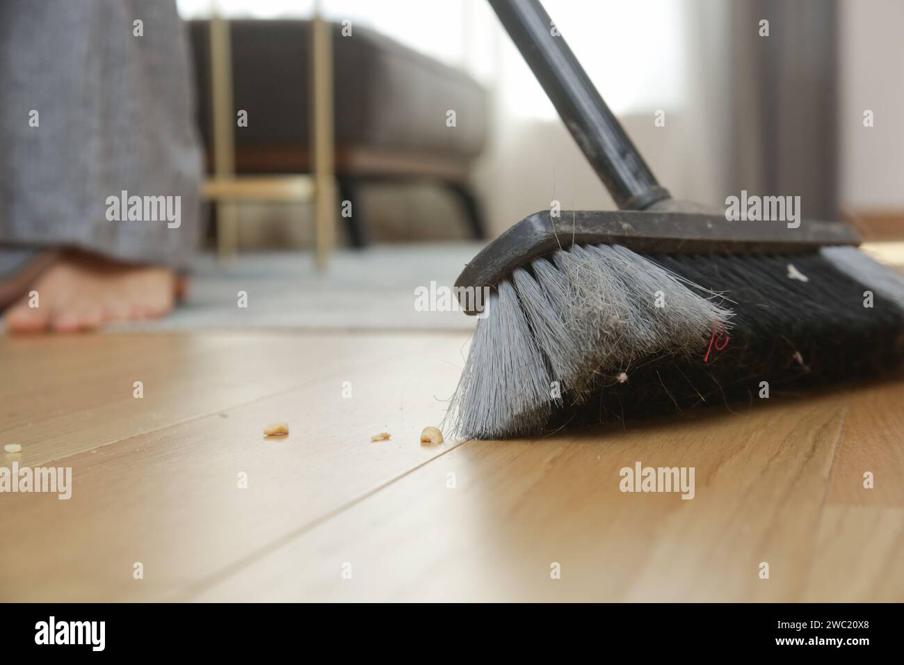 Pulizia della casa. Primo piano di una donna che fa i lavori domestici, tiene una scopa e spazza il pavimento Foto Stock