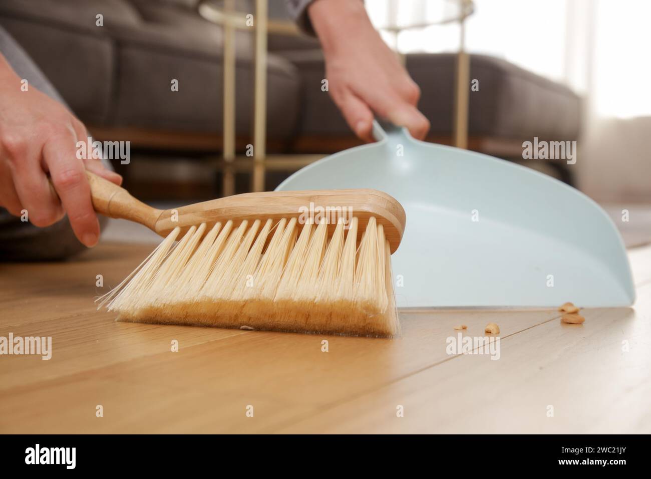 Immagine ravvicinata di un appartamento di donna che pulisce le mani con una scopa piccola e una padella Foto Stock
