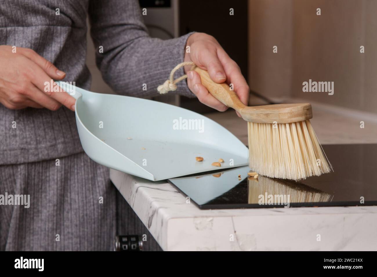 Immagine ravvicinata di un appartamento di donna che pulisce le mani con una scopa piccola e una padella Foto Stock