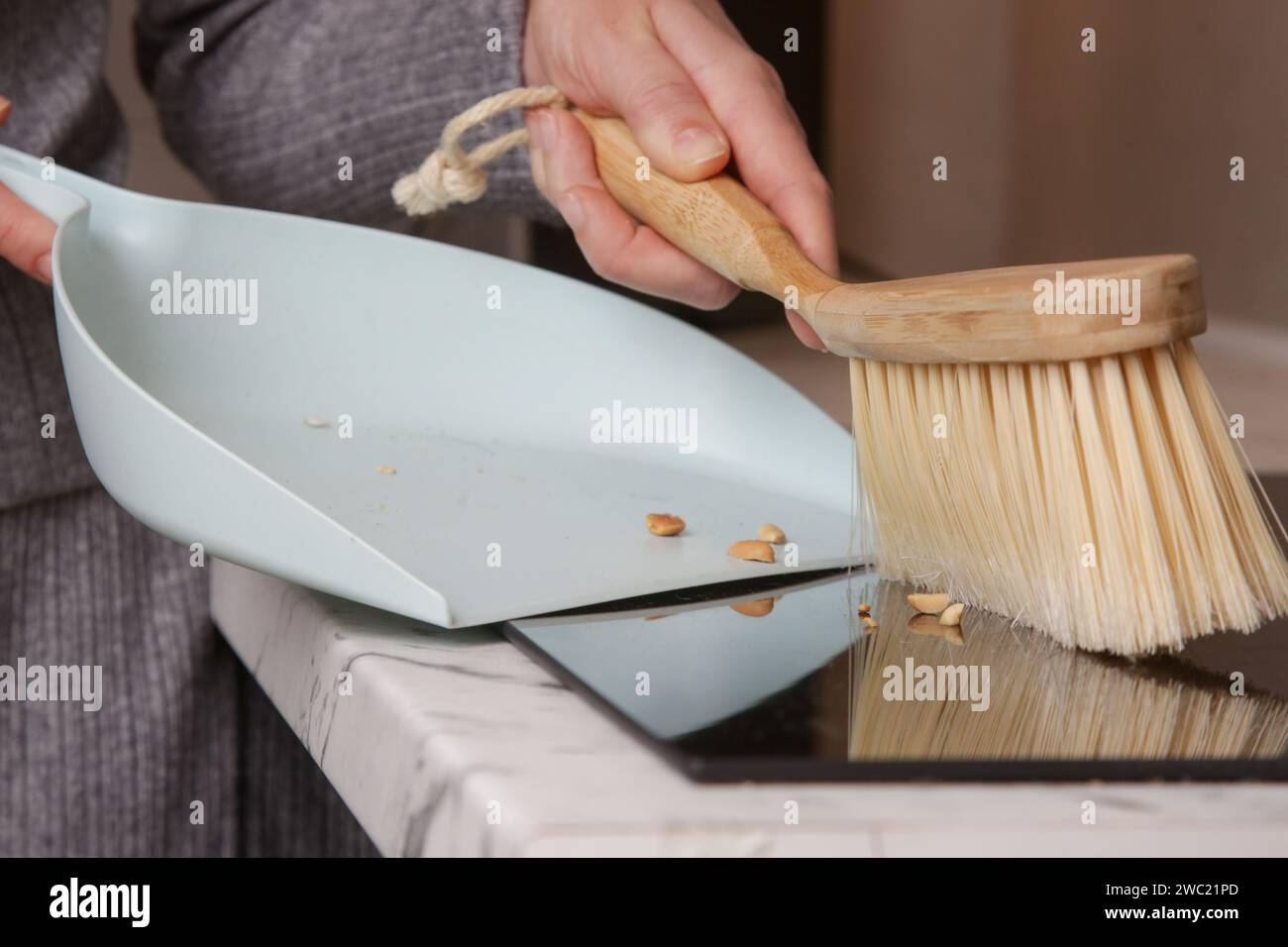 Immagine ravvicinata di un appartamento di donna che pulisce le mani con una scopa piccola e una padella Foto Stock