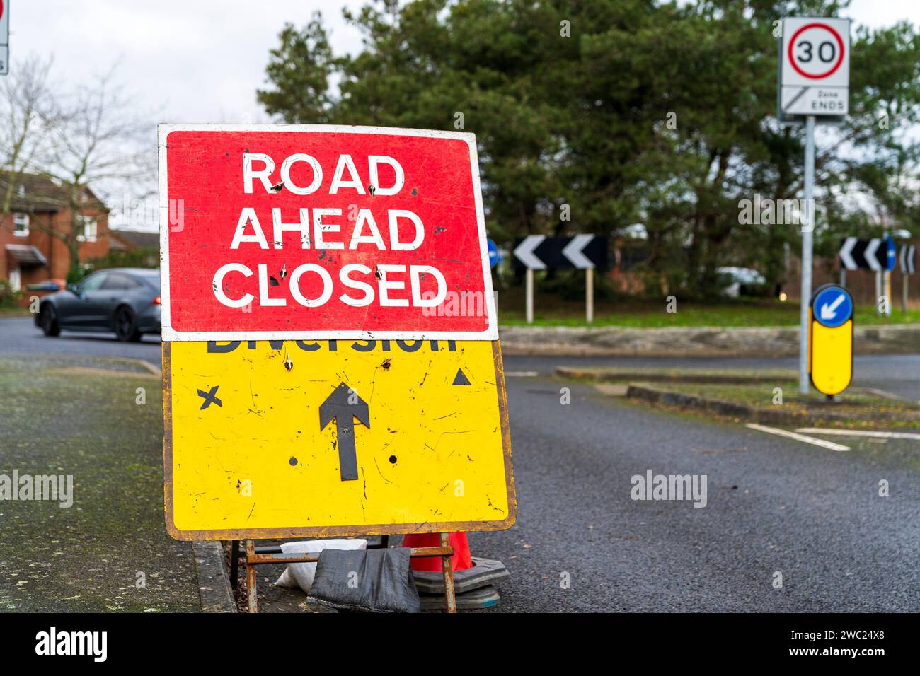 Cartello britannico rosso "Road ahead CLOSED" con un altro cartello giallo, "diversion" con croce nera e triangolare che indica quale lato è chiuso. Foto Stock