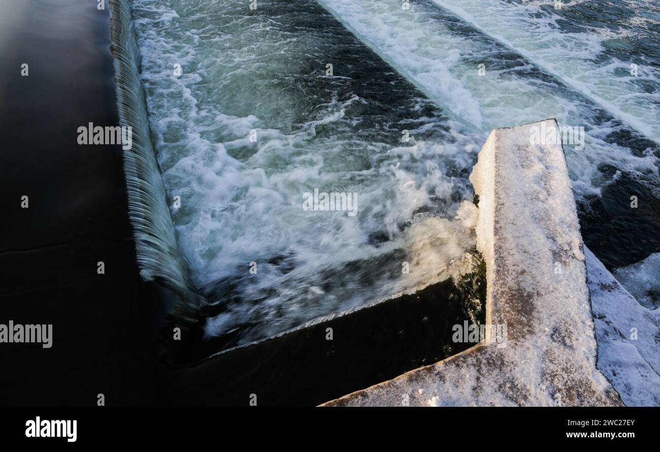 Cascata d'acqua sul gradino della diga nel canale fluviale. Foto Stock