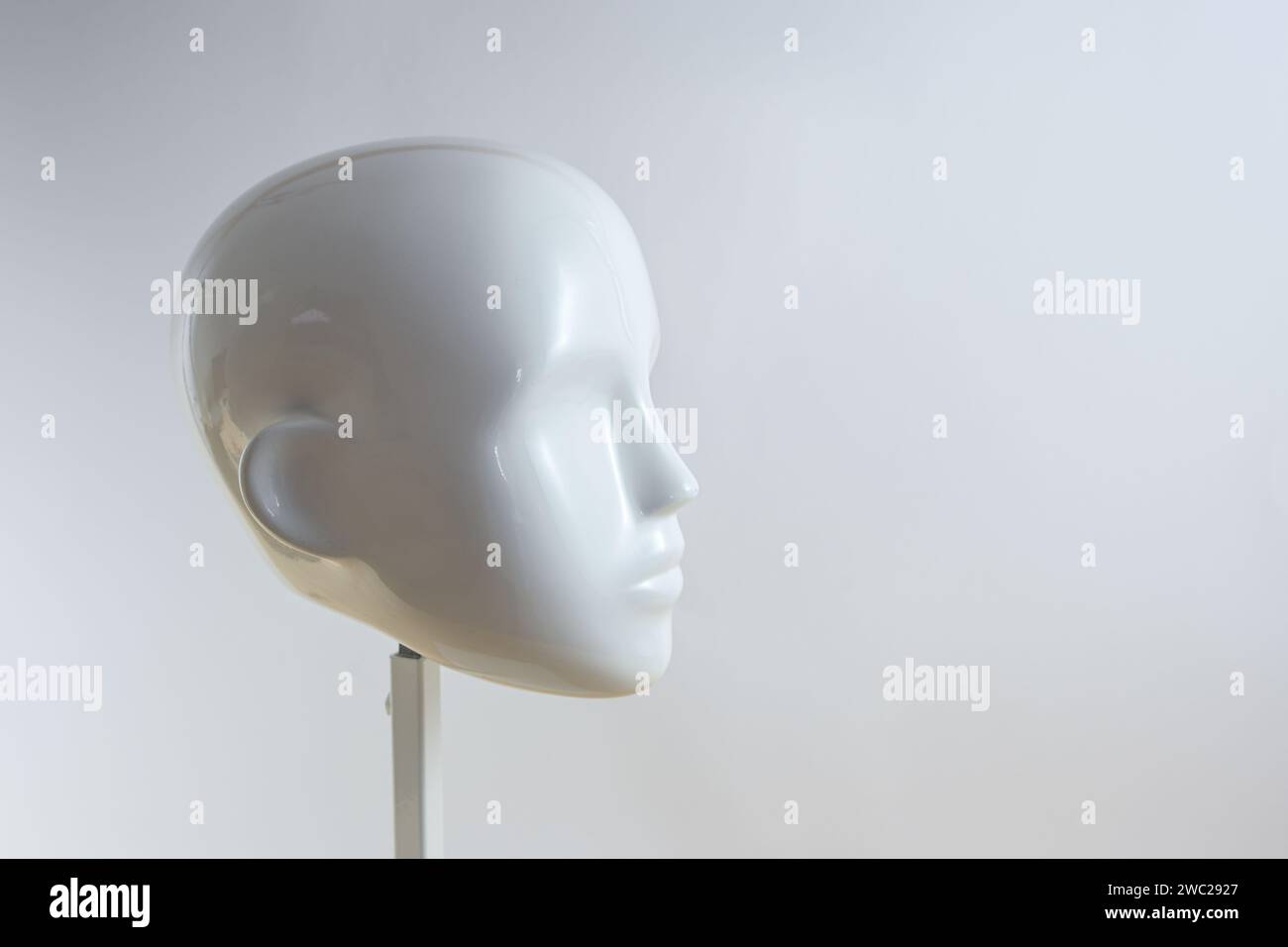Testa bianca neutra di un manichino in stile minimalista su un piedistallo in metallo su sfondo grigio beige chiaro, spazio di copia e messa a fuoco selezionata Foto Stock
